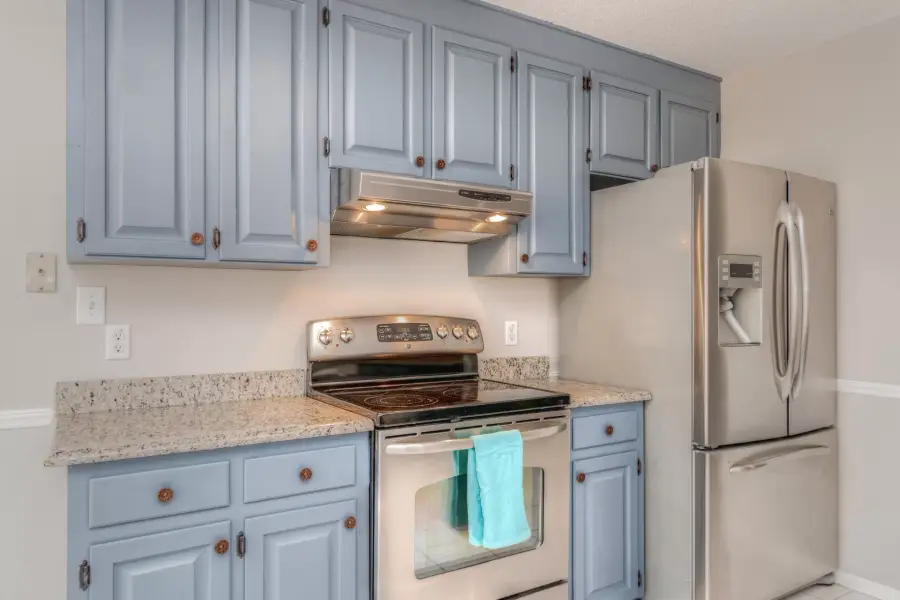Kitchen cabinets refinished in a soft gray blue around a stainless range