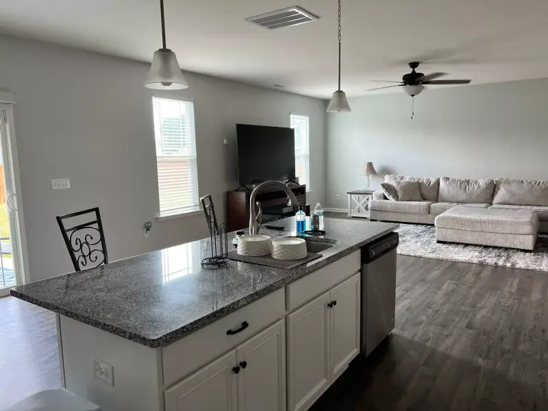 An open concept kitchen with painted cabinets and a granite breakfast bar