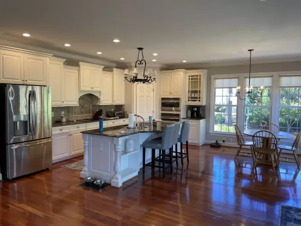 A kitchen with white painted cabinets, a dark island and hardwood flooring