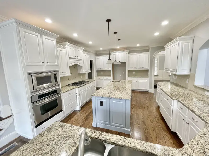 White painted kitchen cabinets with stainless appliances and a granite worktop