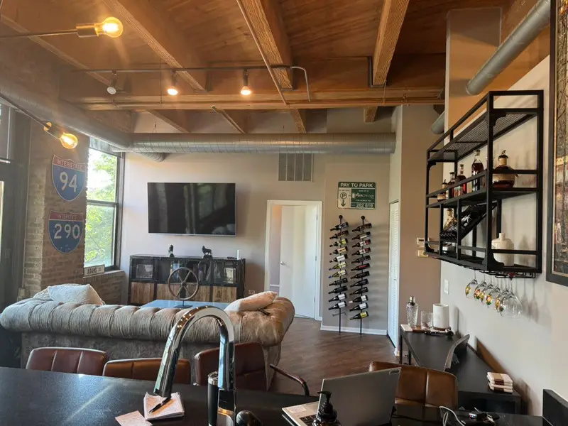 A bar and lounge with an exposed timber ceiling, painted gray walls and black shelving