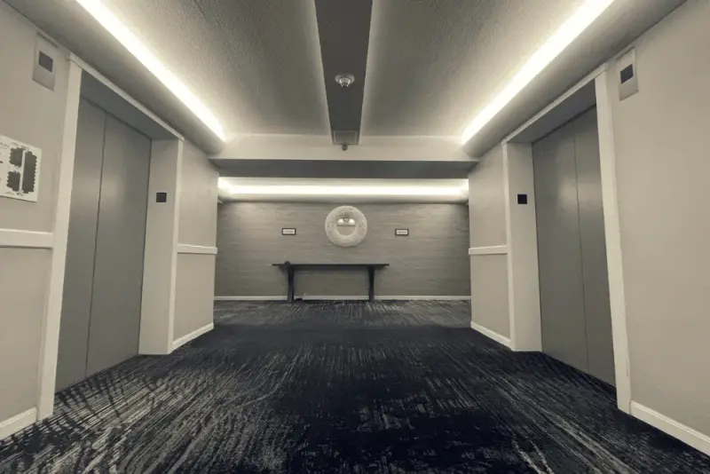 A commercial lobby corridor with freshly painted gray walls and a recessed light cove