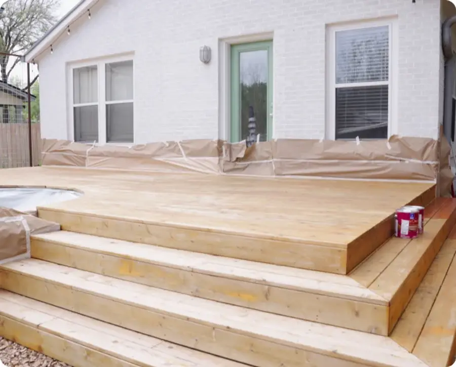 Freshly stained cedar deck steps with the surrounding area masked off during the job