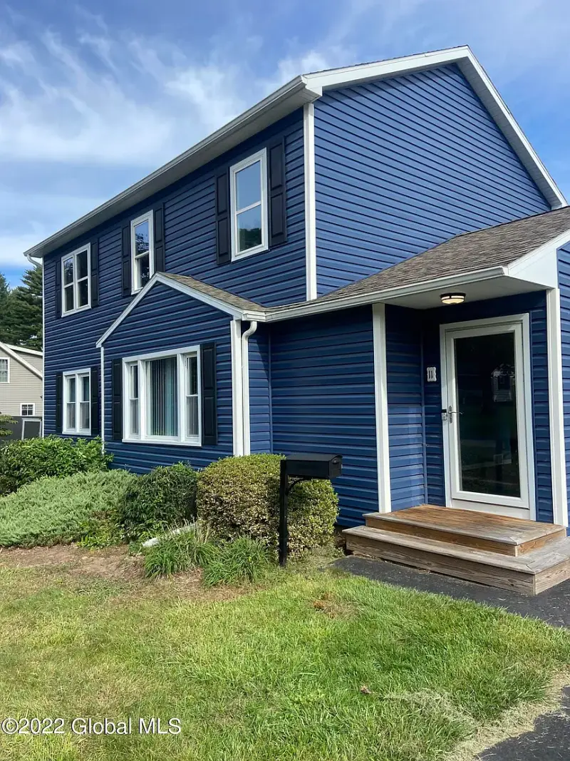 A navy blue sided home with crisp white window trim and a painted entry