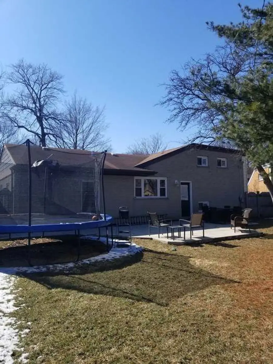 A repainted ranch home seen from the back garden, with a patio and open yard