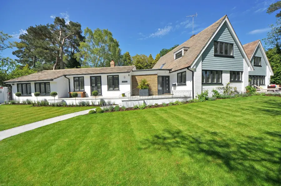 A white cottage style home with dark trim and a freshly cut lawn