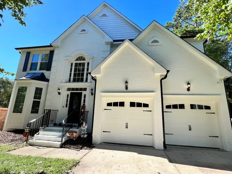 A white suburban home with twin gables and repainted garage doors