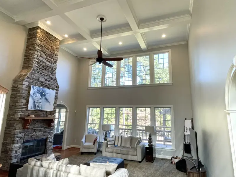 A double height living room with a coffered ceiling, stone fireplace and freshly painted walls