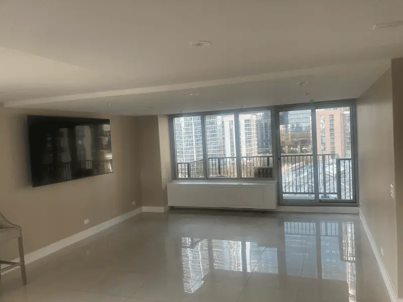 A high-rise condo living room painted in a warm greige, with tile floors and a city view