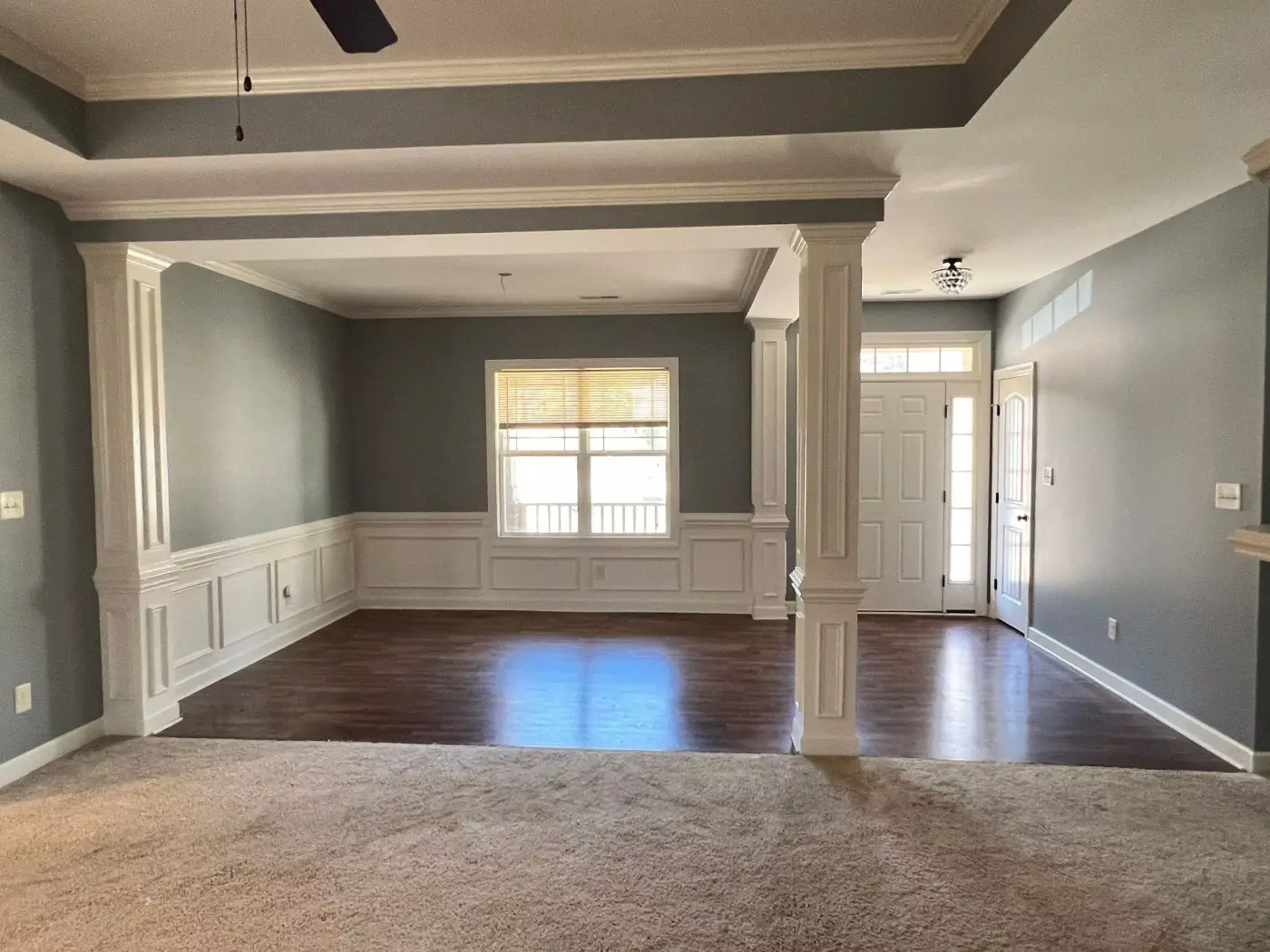 An empty living room with gray walls and white wainscoting after painting