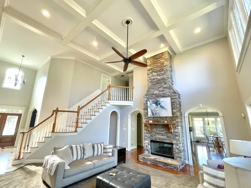 An open living room with a vaulted coffered ceiling and a stone fireplace