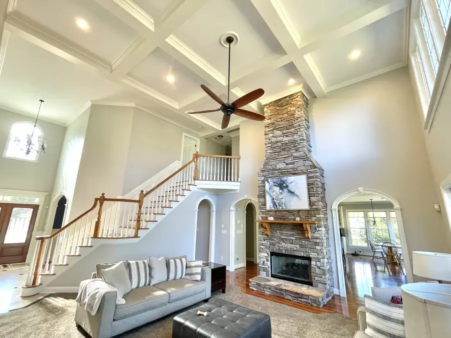 An open living room with a vaulted coffered ceiling and a stone fireplace
