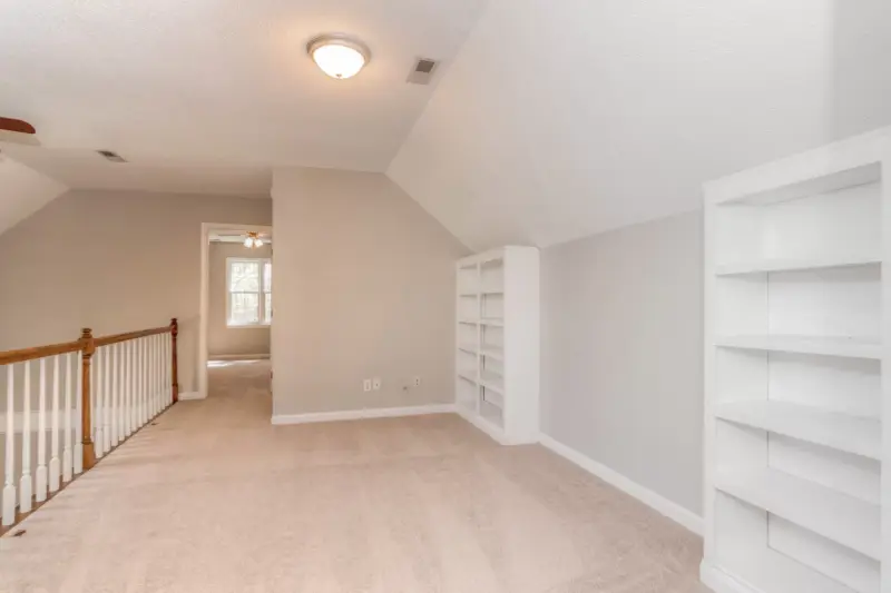 A freshly painted room with a sloped ceiling and white built in shelving