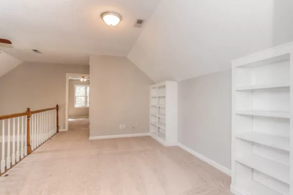 A freshly painted room with a sloped ceiling and white built in shelving